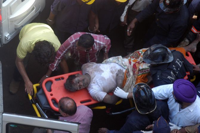 Firefighters rescue a man from the site of building collapse in south Mumbai