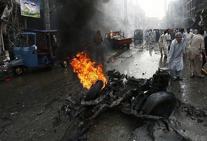 Security officials, rescue workers and residents gather at the site of a bomb attack in Peshawar