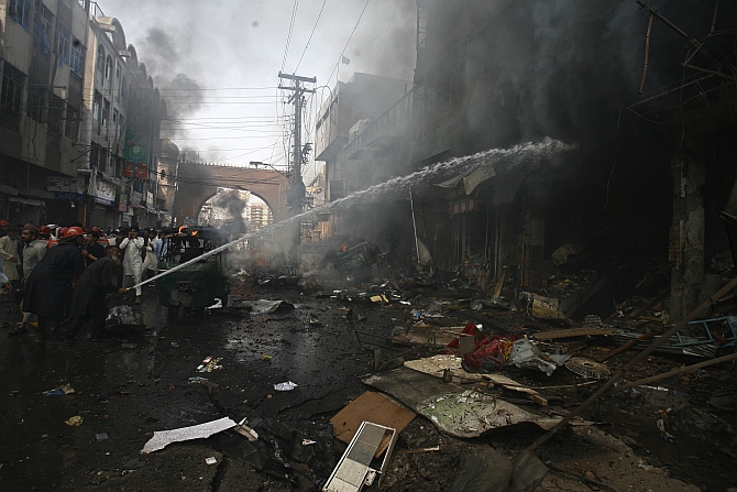 Firefighters extinguish a fire at the site of a bomb attack in Peshawar
