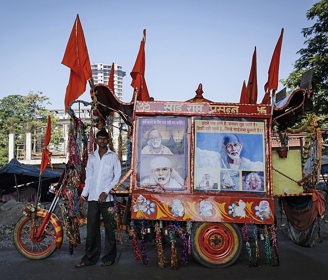 Suresh, 20, who runs a mobile temple, poses along a roadside in Mumbai
