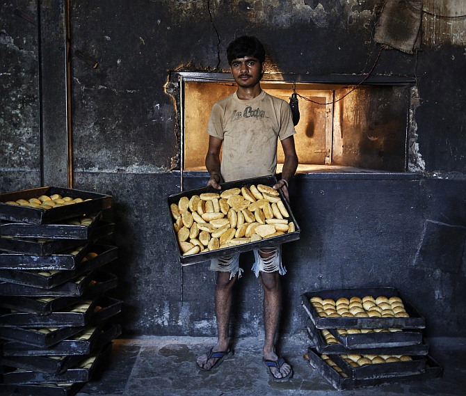Sameer, a 20-year-old worker, poses inside a bakery at a slum in Mumbai March 25, 2014.