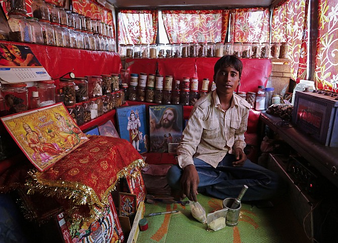 Shamsher Singh, a 19-year-old worker, poses inside a mobile traditional ayurvedic medicine shop in Mumbai.