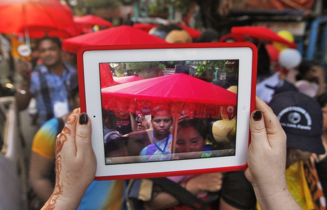 A participant uses a tablet to take pictures of a rally as part of the week-long sex workers' freedom festival at the Sonagachi red-light area in Kolkata.