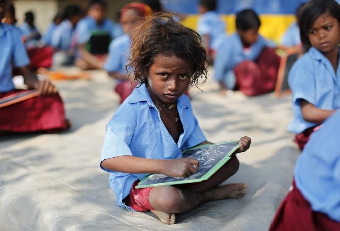 A child whose parents work in a brick kiln attends a class in an open air school at Krishnadevpur village, north of Kolkata.