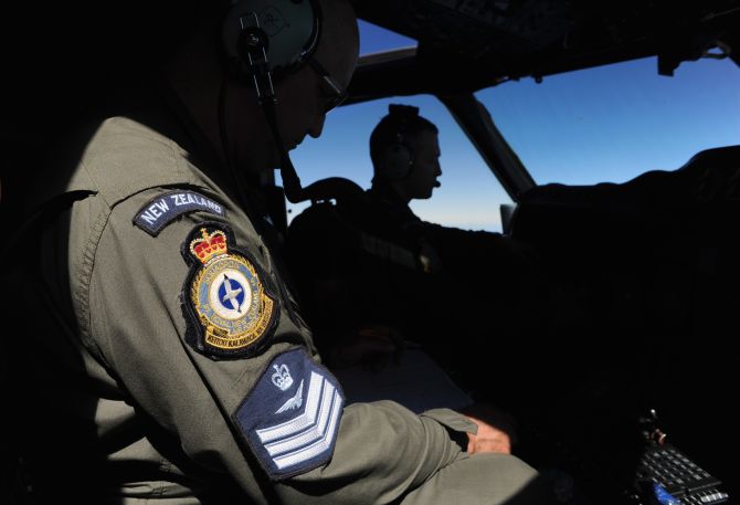 Pilot and captain Flight Lieutenant Timothy McAlevey (R), and flight engineer Chris Poole look from the cockpit of a Royal New Zealand Air Force (RNZAF) P-3K2 Orion aircraft, as they fly over the southern Indian Ocean to continue the search for missing Malaysian Airlines flight MH370