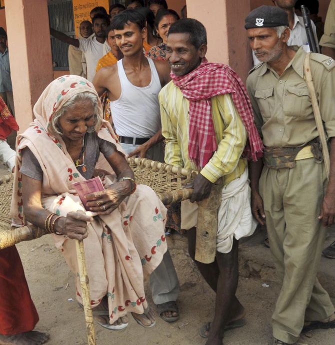 People help 80-year old Jashiya Devi to get to a polling station in Jehanabad in the eastern Indian state of Bihar