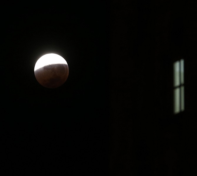 The moon is seen behind a building during a total lunar eclipse over Buenos Aires