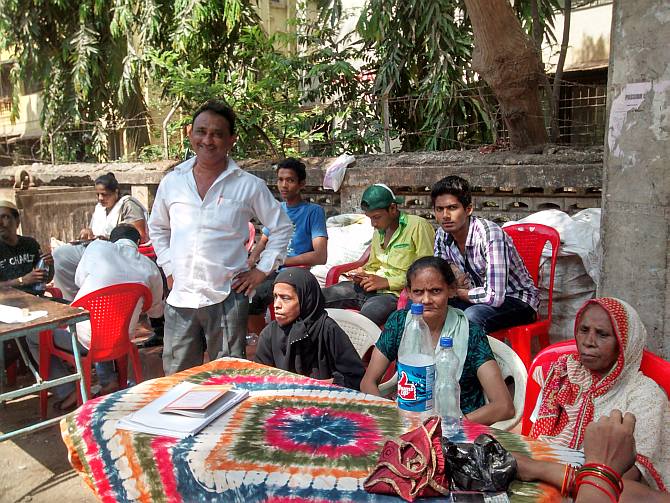 Anwar Shaikh (in white shirt, standing), a Shiv Sena upashakhapramukh stands beside his polling booth agents outside Behrampada. Seated behind him on the red chair is Irfan Syed, a Congress-appointed polling booth agent with his team members
