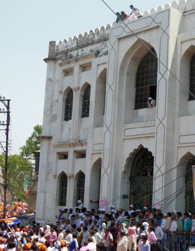 Muslims outside a mosque watch BJP leader Narendra Modi's rally in Varanasi.