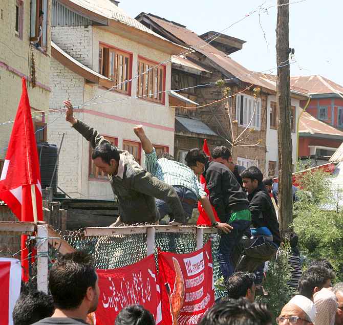 National Conference supporters jump a wall to safeguard themselves following an explosion near a rally venue in Srinagar on Sunday