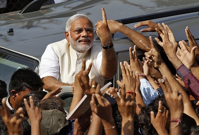 Modi shows his ink-marked finger to his supporters in Ahmedabad