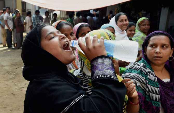 A woman quenches her thirst at a polling station in Howrah district, West Bengal on Wednesday