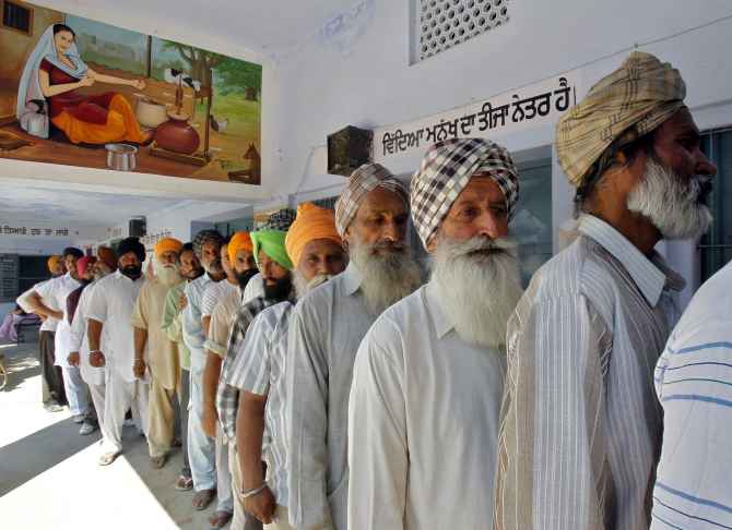 Voters line up to cast their votes outside a polling station at Rasan Hedi village in Punjab
