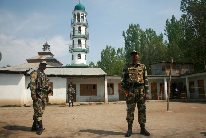 Security personnel stand guard outside an empty polling booth in Srinagar