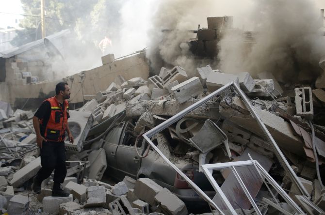 A Palestinian firefighter participates in efforts to put out a fire from the wreckage of a house, which witnesses said was destroyed in an Israeli air strike, in Gaza City.