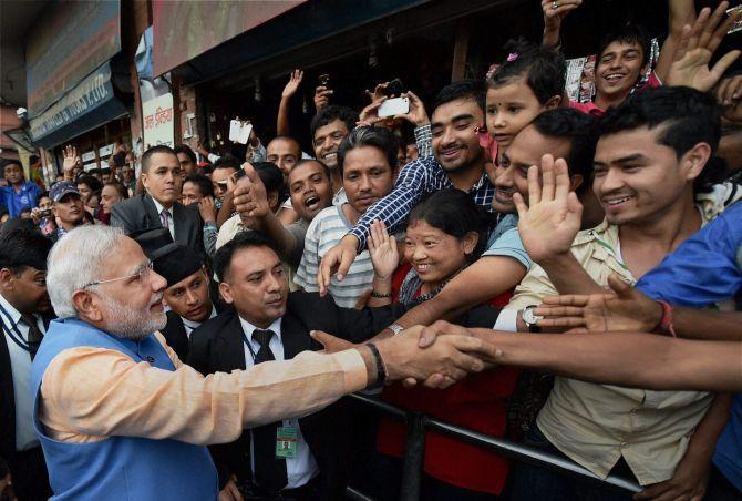 Prime Minister Narendra Modi greets people on the streets on his way back to the hotel after addressing the Nepalese Parliament in Kathmandu