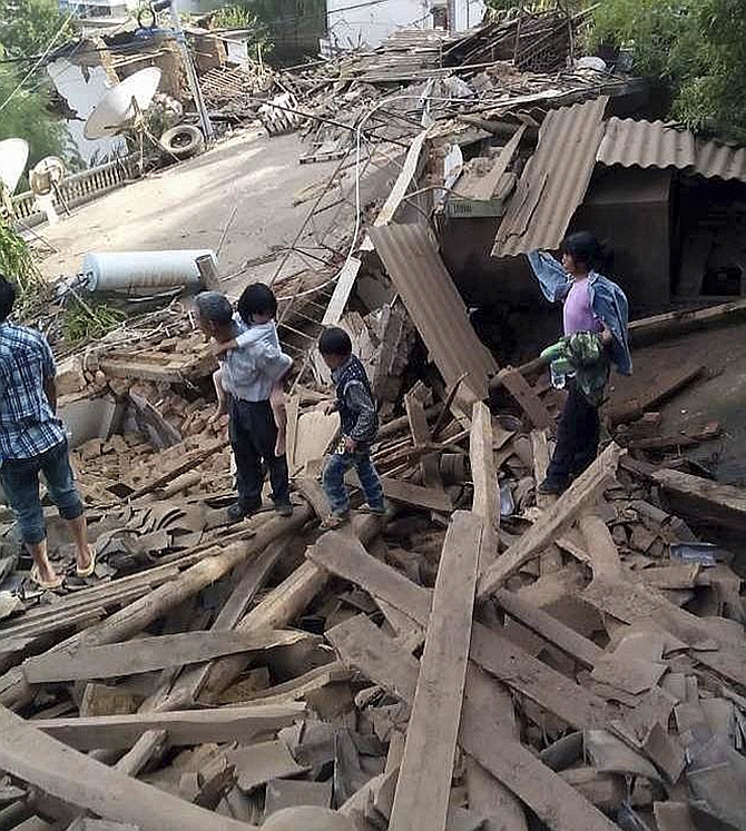 People walk among debris after an earthquake hit Ludian county, Yunnan province