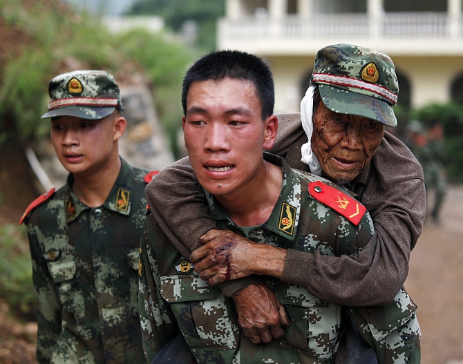 A paramilitary policeman carries an elderly man on his back after an earthquake hit Ludian county of Zhaotong, Yunnan province