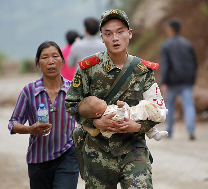 A paramilitary policeman carries a baby in his arms after an earthquake hit Ludian county 