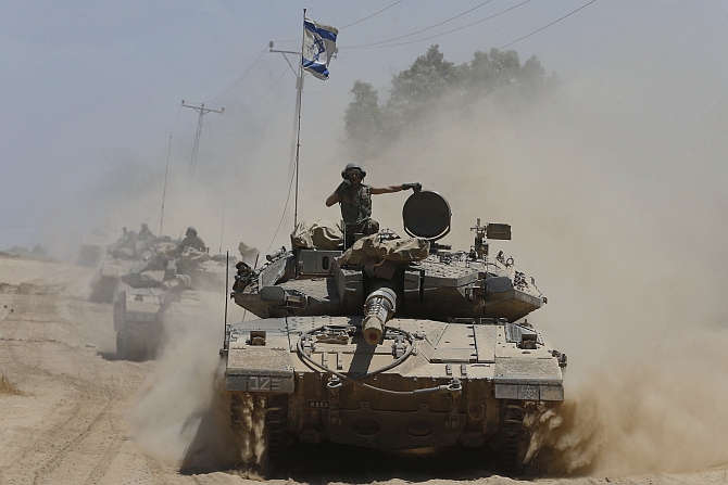 An Israeli soldier rides atop a tank near the border with the Gaza Strip 
