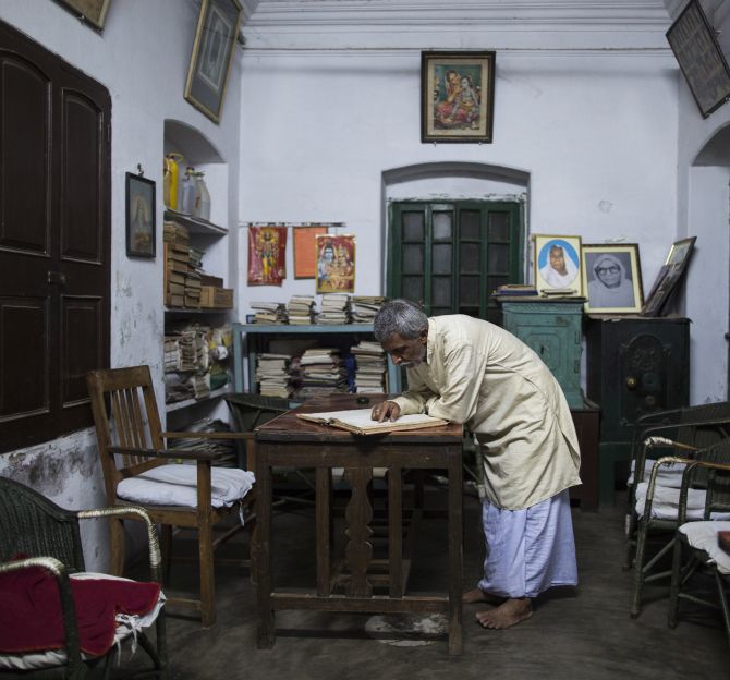 Bhairav Nath Shukla, manager of Mukti Bhavan looks through the records inside his office in Varanasi.
