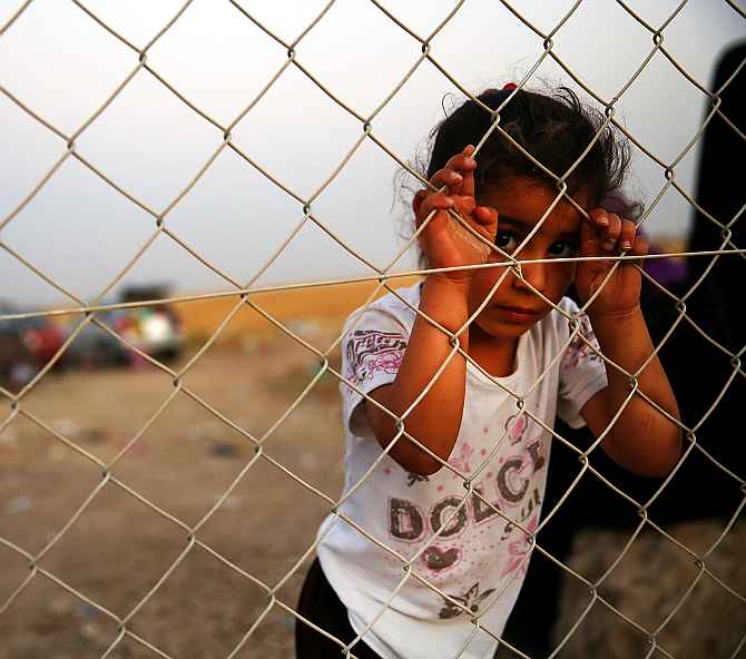 A child waits with her family outside a temporary displacement camp for Iraqis caught up in the fighting against ISIS in and around Mosul. (Inset) Dr Bonny Ibhawoh