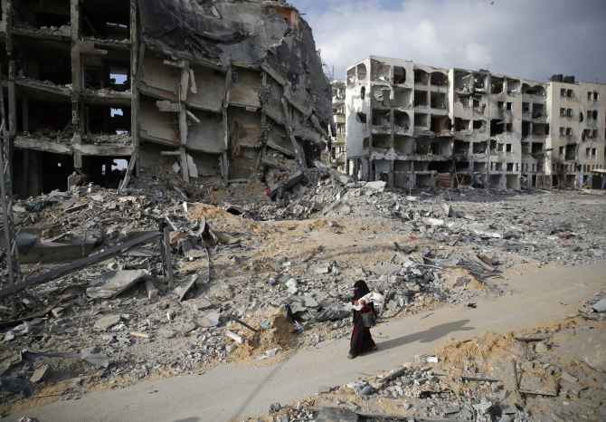 A Palestinian woman walks past buildings destroyed by Israeli air strikes and shelling at Beit Lahiya, Gaza Strip.