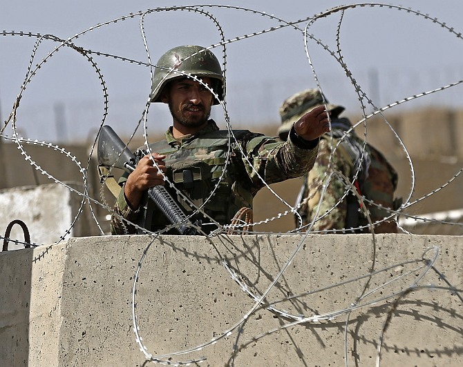 An Afghan National Army soldier keeps watch at the gate of a British-run military training academy Camp Qargha, in Kabul August 5