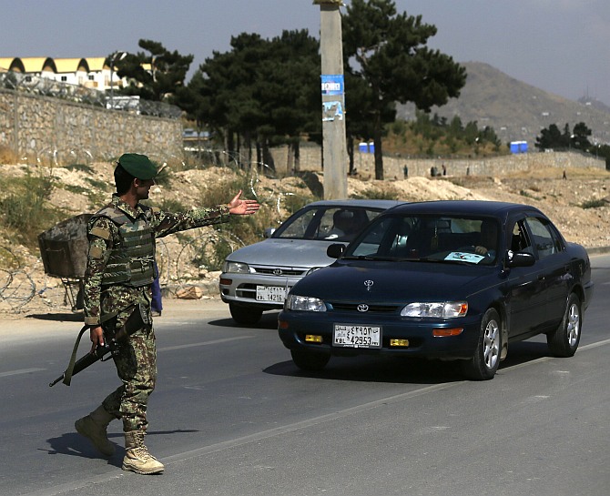 An Afghan National Army soldier gestures at a car at the gate of a British-run military training academy Camp Qargha, in Kabul