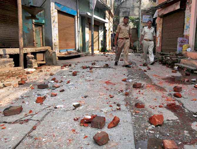 Policemen walk on a road littered with bricks and stones thrown during a communal clash in Muzaffarnagar.