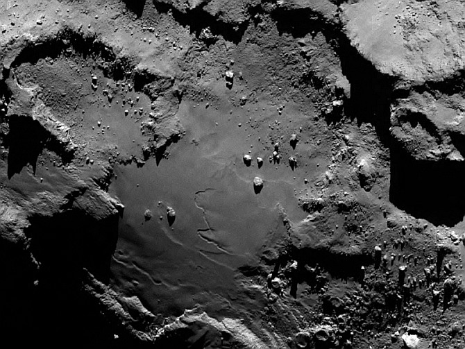 Stunning close up detail focusing on a smooth region on the 'base' of the 'body' section of comet 67P/Churyumov-Gerasimenko. The image was taken by Rosetta's OSIRIS narrow-angle camera and downloaded on August 6. The image clearly shows a range of features, including boulders, craters and steep cliffs. The image was taken from a distance of 130 km and the image resolution is 2.4 metres per pixel.