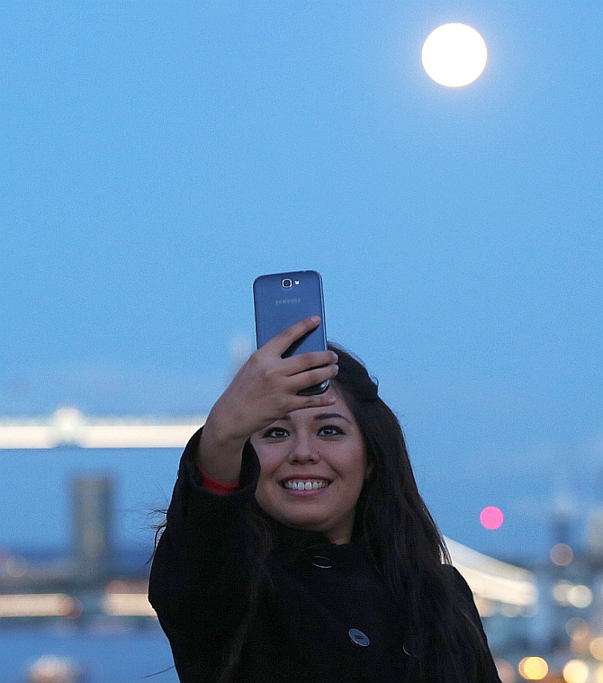 A woman takes a selfie as the supermoon rises over Tower Bridge in London