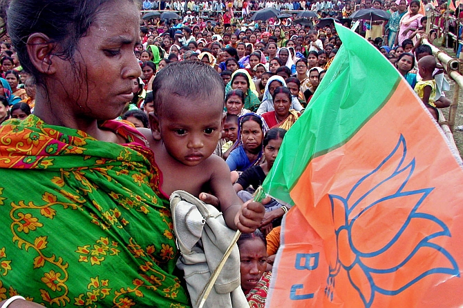 An woman holds her child and flag of ruling Bharatiya Janata Party  during an election campaign rally