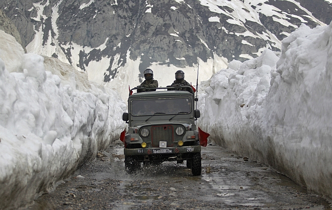 Indian Army soldiers travel in a vehicle on a mountainous road covered by snow after the Srinagar-Leh highway