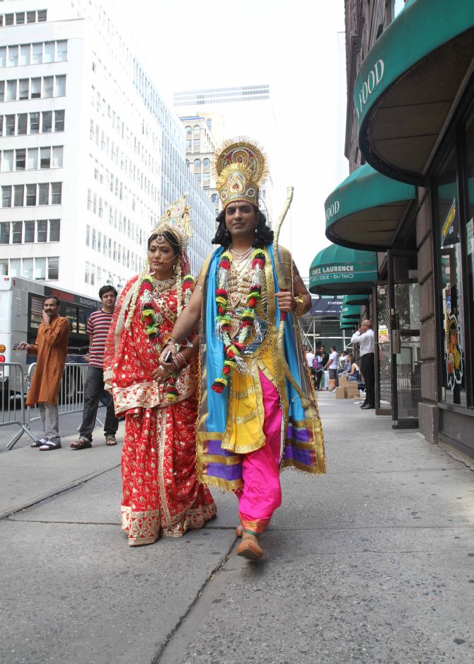A couple dressed as Hindu gods walk down a street in New York, as they participate in the parade