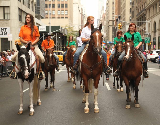 Women dressed in the different colours of the Indian flag on horses become a part of the parade. 