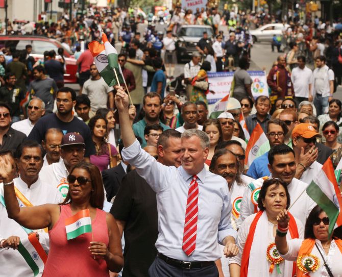 New York City Mayor Bill de Blasio, waves an Indian flag and walks among the public during the parade