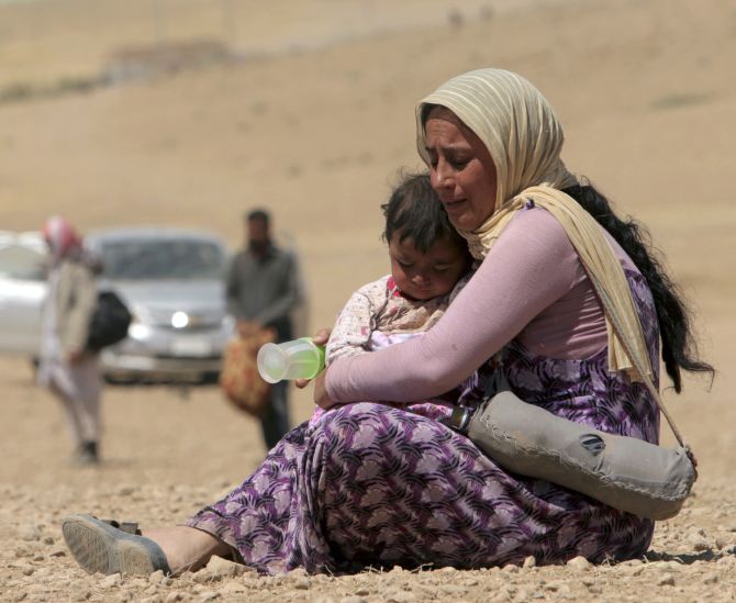 A displaced woman and child from the minority Yazidi sect, fleeing violence from forces loyal to the Islamic State in Sinjar town, rest as they make their way towards the Syrian border