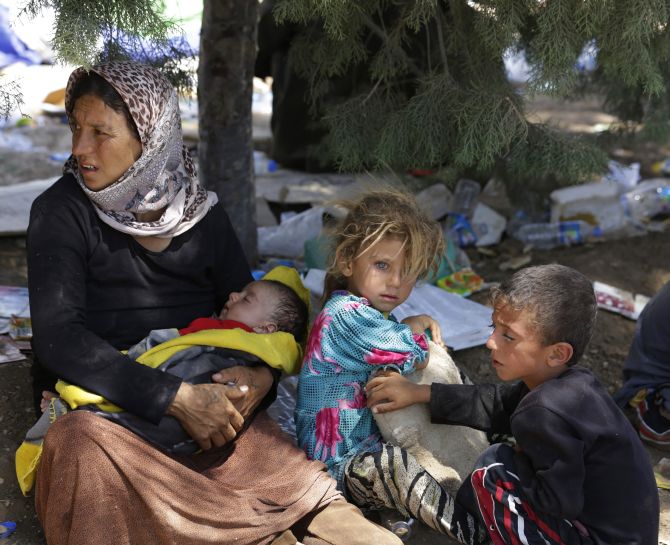 A displaced family from the minority Yazidi sect wait for food and water.