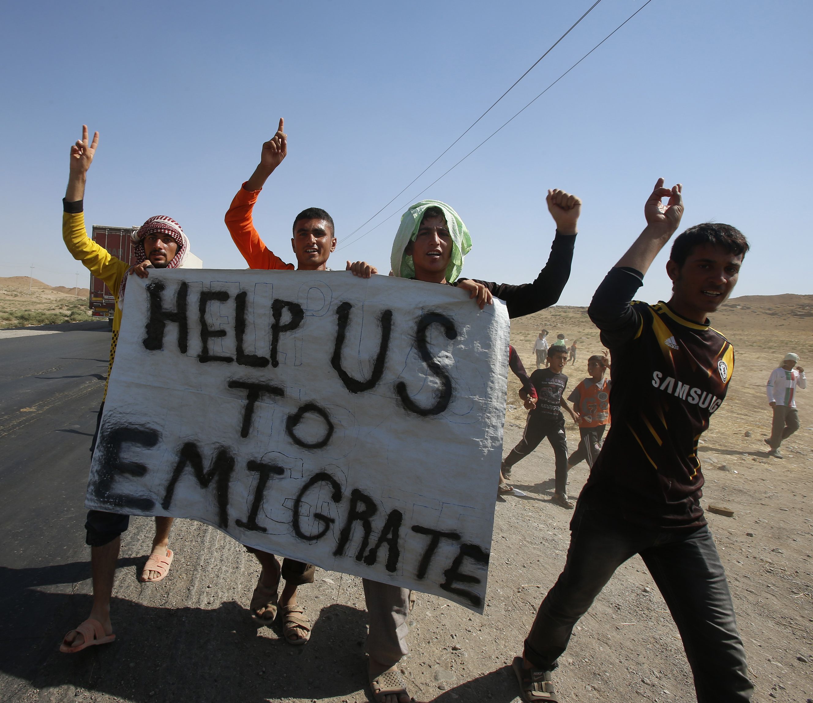Displaced people from the minority Yazidi sect, who fled the violence in the Iraqi town of Sinjar, hold a banner as they take part in a demonstration at the Iraqi-Syrian border crossing in Fishkhabour, Dohuk province.