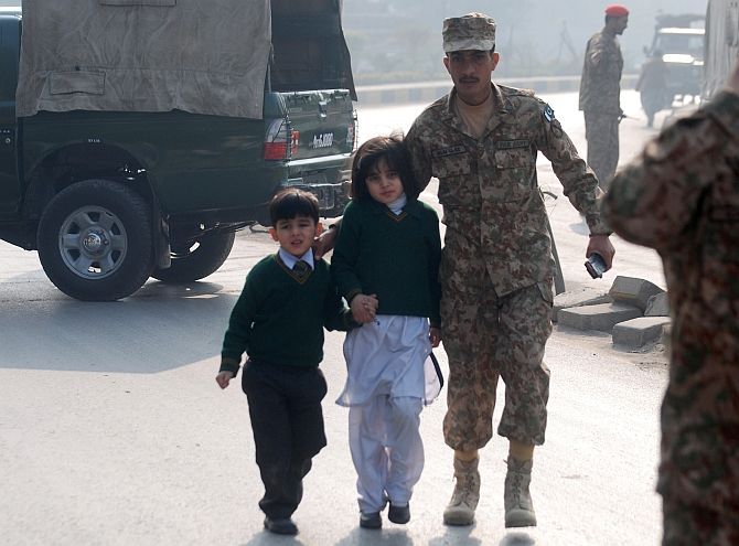 A soldier escorts children from the Army Public School that came under attack from Taliban terrorists in Peshawar. Photograph: Khuram Parvez/Reuters