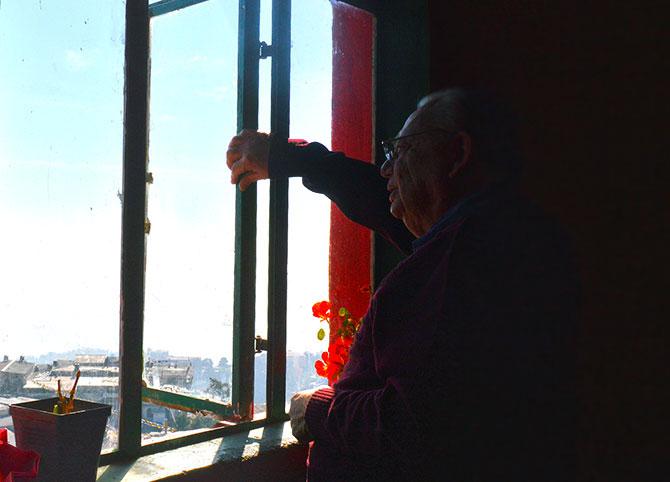 Ruskin Bond stands beside the window in his room