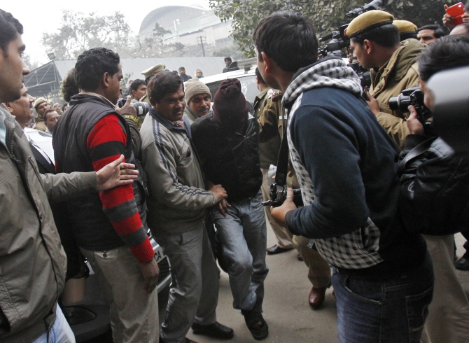 Plain-clothes police escort a man (face covered) accused of a gang rape outside a court in New Delhi