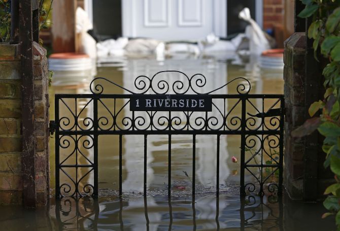 The front gate to a house is seen surrounded by water after the river Thames flooded the village of Wraysbury, southern England, Monday