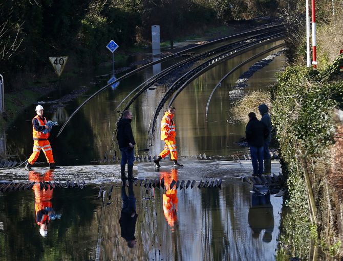 Railway workers are seen crossing the tracks after the river Thames flooded the railway in the village of Datchet, southern England.