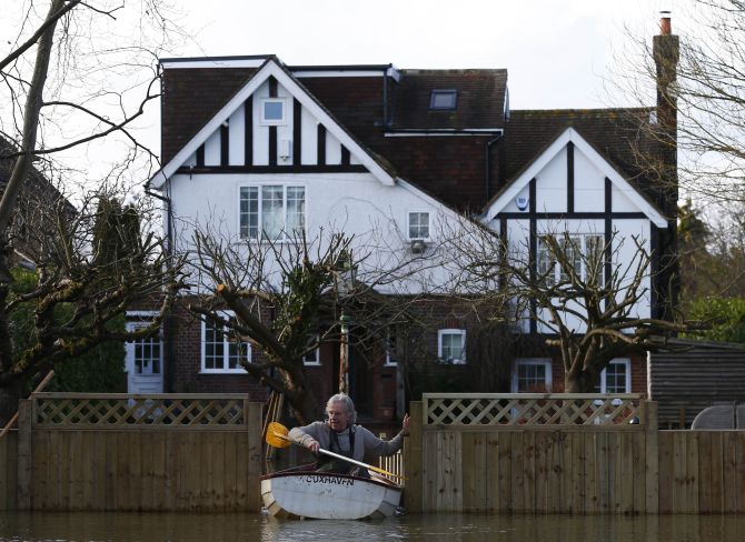 Nigel Gray leaves his home in a rowing boat after the river Thames flooded the village of Wraysbury, southern England