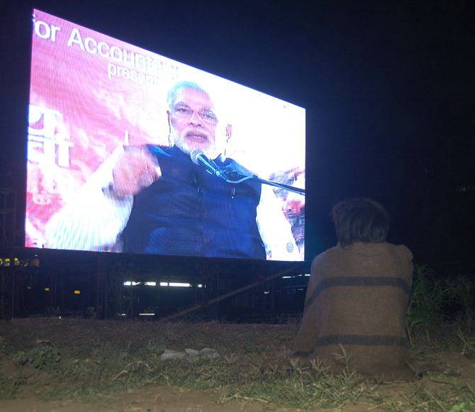 A lone street kid watching Narenda Modi's address on a giant screen at Karnavati Park