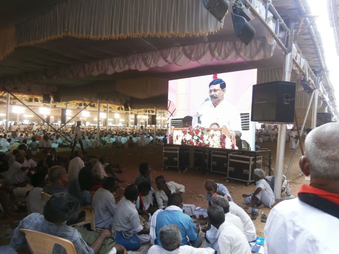 Giant screens amid thousands of supporters at a pandal spread across acres
