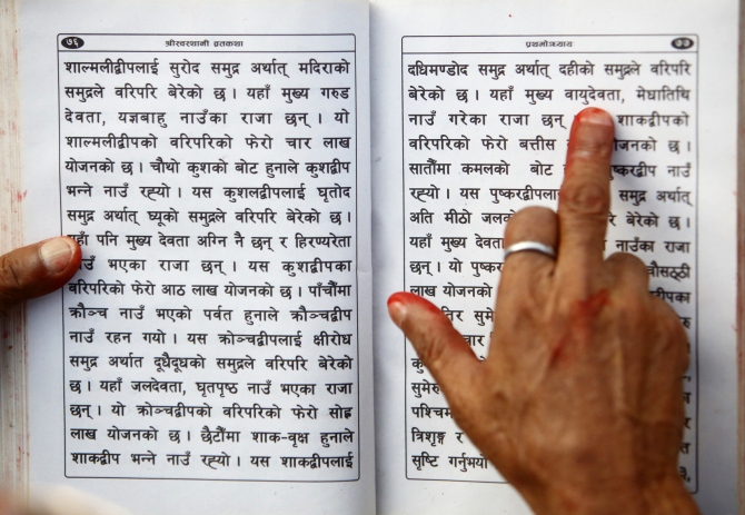 A Hindu holy man holds the holy book on his hand as he recites verses