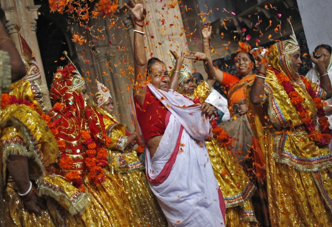 A woman throws flower petals and dances with widows dressed as Krishna's consort, Radha, during celebrations to mark Janmashtami festival at the Meera Sahavagini ashram in Vrindavan